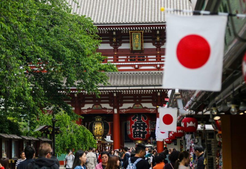 Banderas de Japón en una calle comercial, frente a la puerta roja de un templo